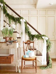 a staircase decorated for christmas with greenery and presents on the bannister rail