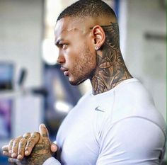 a man with tattoos on his arm and chest looking off to the side while holding his hands together