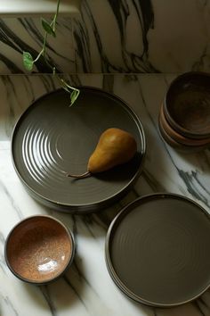 three plates and a pear on a marble table