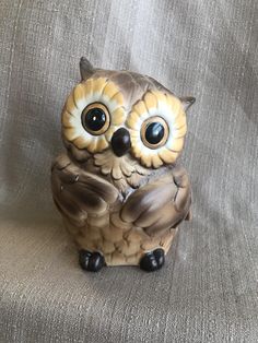 an owl figurine sitting on top of a gray cloth