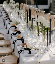 a long table with white flowers and black ribbon