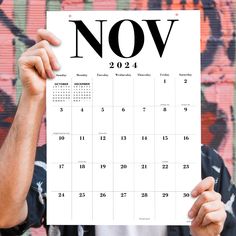 a man holding up a calendar with the word now written on it in front of his face