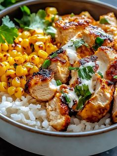 a bowl filled with rice and chicken next to corn on the cob, garnished with cilantro