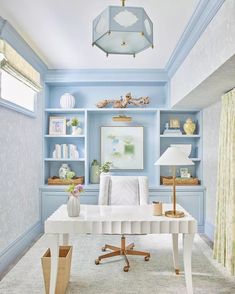 an office with blue walls and white desk in the center, along with bookshelves