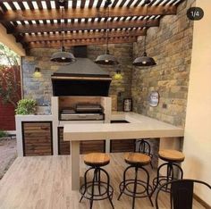 an outdoor kitchen with bar stools and grill