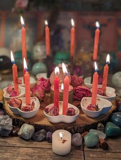 candles are lit in small bowls on a wooden tray with rocks and stones around it