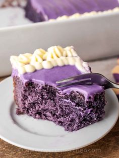 a slice of purple cake with white frosting and a fork in it on a plate