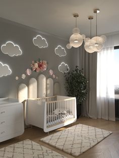 a baby's room decorated in white and pink with clouds on the wall above it