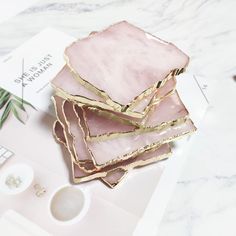 three pieces of pink and gold marble sitting on top of a white table next to a plant