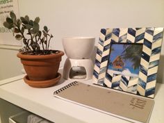 a desk with a coffee maker, potted plant and photo frame on top of it