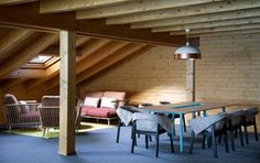 an attic with wooden walls and flooring has chairs around a table in the center