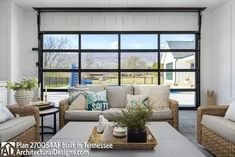 a living room with wicker furniture and large windows