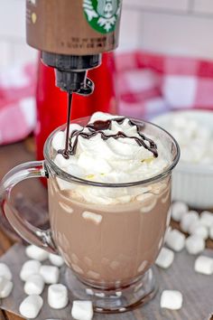 there is a cup of hot chocolate and marshmallows on the table