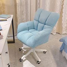 a blue office chair sitting on top of a white desk next to a bed in a bedroom