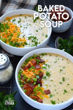 two bowls filled with baked potato soup on top of a black table next to some parsley