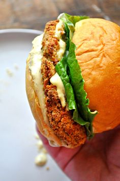 a hand holding a sandwich with lettuce and cheese