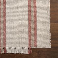 the red and white striped rug is laying on top of a wooden floor next to a table