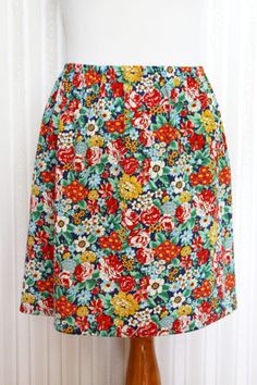 a colorful skirt on a mannequin stand in front of a white wall and window