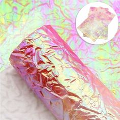 a roll of foil sitting on top of a white surface with pink and yellow colors