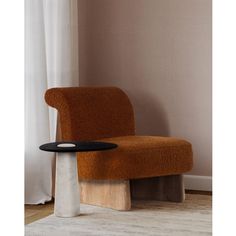 an orange chair sitting on top of a wooden table next to a white curtained window