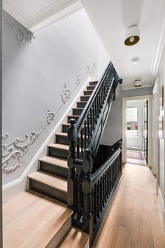 a staircase with black railing and wood flooring next to a white painted stair case