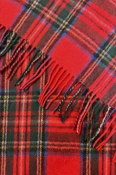 a red and black plaid blanket with fringes on the edges, close - up