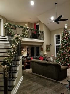 a living room filled with furniture and christmas tree next to stairs in front of a staircase case