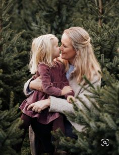 a mother and her daughter hugging each other in the middle of a christmas tree farm