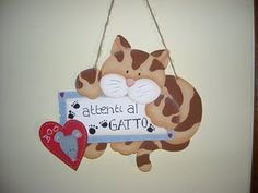 a cat hanging from the side of a wall with a sign that says,'attentional gatto '