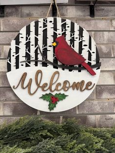 a welcome sign hanging from the side of a brick building with a cardinal on it