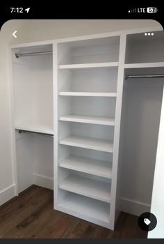 an empty closet with white shelves and wooden floors