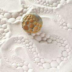 a ball sitting on top of a bed covered in white and gold circles next to a wall