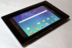 a tablet sitting on top of a white table next to a black case with icons