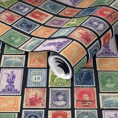 a roll of colorful postage on top of a black tablecloth covered in different colored stamps