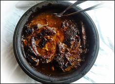 a bowl filled with meat and sauce on top of a white table cloth next to a spoon