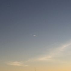 an airplane is flying high in the sky above some buildings and water at sunset or dawn