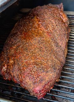 a piece of meat cooking on top of a bbq grill with lots of seasoning