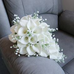 a bouquet of white flowers sitting on top of a gray couch next to a pillow