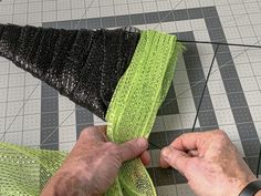 a man is working on some type of material with scissors and thread in his hands