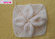 a crocheted white square with a large bow on the front and bottom, sitting on a yellow surface