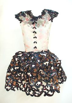 a dress made out of black and white fabric with flowers on the bottom, in front of a white wall