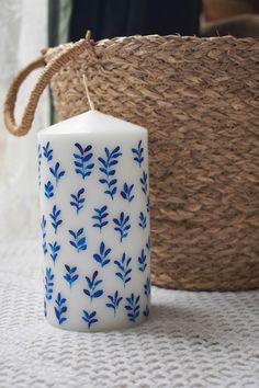 a blue and white candle sitting on top of a table next to a wicker basket