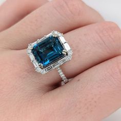 This beautiful art deco ring features a vibrant London blue topaz set in 14k white gold with roudnd and baguette diamond accents. A statement ring design perfect for an eye catching engagement or anniversary. This ring also makes a beautiful birthstone ring for your loved ones. The occasions to show off this ring are endless - mother's day, graduation, wedding, birthday, date night, Christmas, etc. :) Item Type: Ring Stone: London Blue Topaz Weight: 5.4cts Cut: Faceted Shape: Emerald Cut Head size: 11x9mm Metal 14k/4.02g Diamonds S/I GH: 32/0.84cts Sku:AJR252/3458 Our piece can be made... - In dual tone, 18k gold, or platinum - To fit your gem's unique size and shape - With higher color and clarity of diamonds - As bezel set, prong set, etc. - To stack with your bands - With different gem Blue Topaz Ring Engagement, Luxury Art Deco Topaz Ring With Prong Setting, Blue 14k White Gold Jewelry With Baguette Cut, Blue Radiant Cut Topaz Ring Fine Jewelry, Blue Baguette Cut 14k White Gold Jewelry, Gia Certified Blue Topaz Ring With Emerald Cut, Luxury Emerald-cut Topaz Ring, Luxury Timeless Emerald-cut Topaz Ring, Emerald And Diamond Engagement Ring