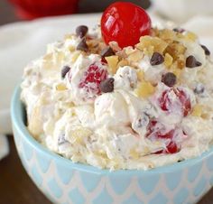 a bowl filled with ice cream and cherries on top of a table next to an apple