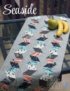 a quilted table with two bananas on it and the words seaside written in white