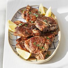 a plate full of cooked meat with lemon wedges