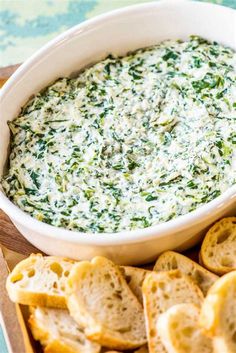 a white bowl filled with spinach dip surrounded by crackers