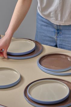 a woman placing plates on top of a table with blue and brown trimmings