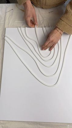 a woman is working on an art project with white paper and plastic glue, while she holds her hands over the edge of a large piece of plywood