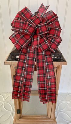 a red and black plaid bow sitting on top of a wooden table next to a white wall